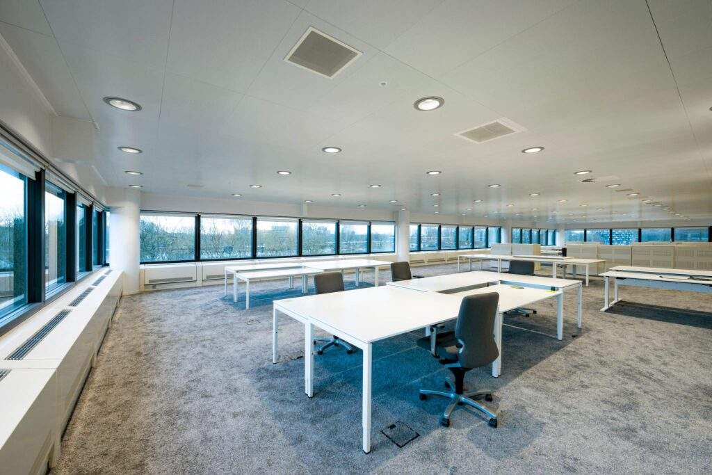 Ruime en moderne kantoortuin aan de Prof. E.M. Meijerslaan met witte bureaus, grijze stoelen en grote raampartijen.